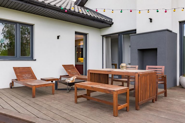 A patio with wooden furniture and chairs on the deck.