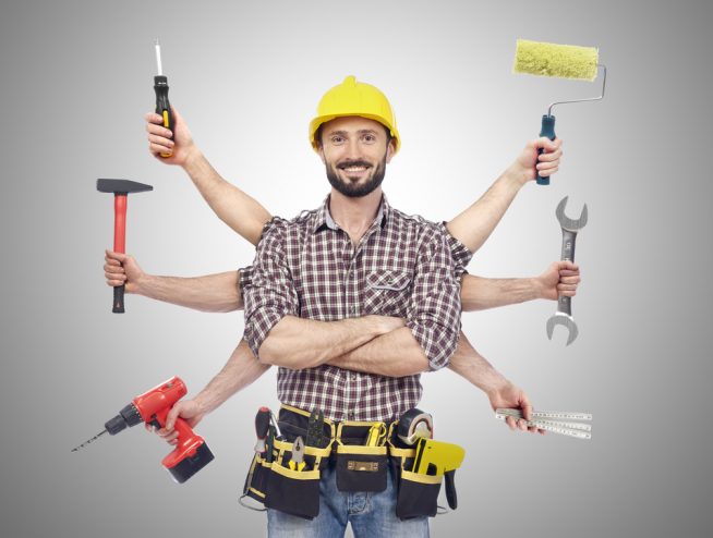 A man with tools in his hands and wearing a hard hat.