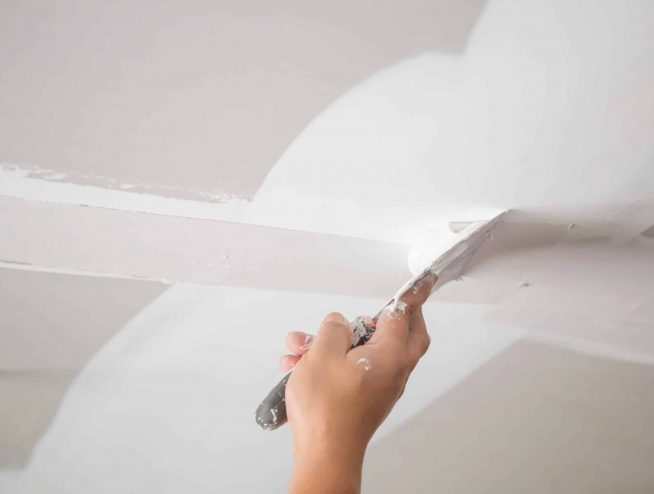 A person is cutting the ceiling of a room.